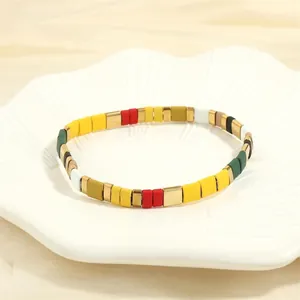 Detail of colorful bohemian stacked beads on a white ceramic tray with soft lighting