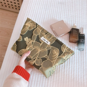 Detailed view of dark green jacquard fabric with golden leaf texture and brand tag