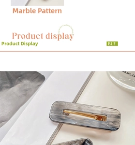 Detail showing rectangular acrylic hair clip with grey ink pattern and gold metal base