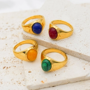 Close-up of vintage 18k gold plated signet rings with colorful agate stones on stone base