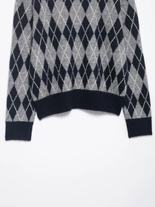 Detail of navy and grey argyle knit sweater showing ribbed cuffs and soft texture
