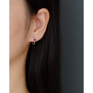 Detailed close-up of a beaded silver hoop earring with a black stone on model