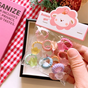 Close-up of colorful kids hair ties with star beads in clear bag on plaid background