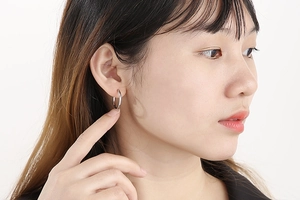 Close-up of a model wearing a silver stainless steel hoop earring in a minimalist style