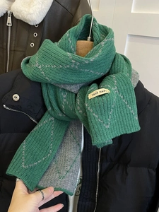 Detail showing green and gray knit scarf with geometric stitching and handmade label