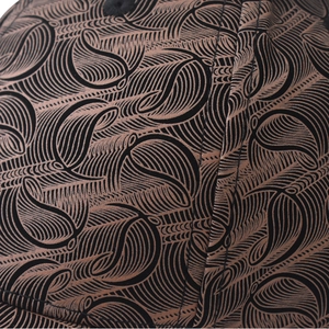 Gros plan du tissu à motifs losanges et détails de feuilles en métal sur la casquette