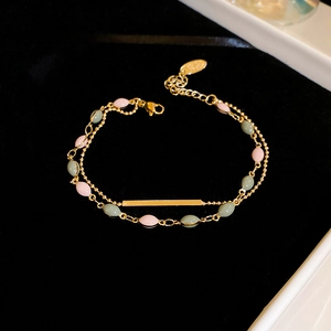 Detail of double-layer gold plated bracelet with pink and green beads on black velvet