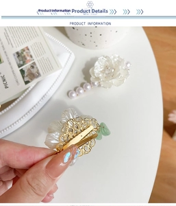 Dettaglio del fermaglio per capelli camelia con perle e pendente in giada su base dorata