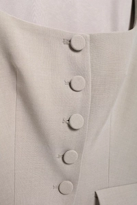 Macro shot of tweed fabric texture and fabric-covered buttons on a beige square neck top