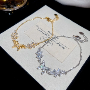 Macro detail of 18k gold plated butterfly and flower bracelet with sparkling zircons