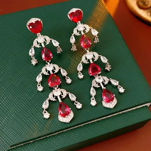 Close-up of luxury silver earrings with red heart stones and shimmering zircon tassels