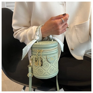 Detail of light green cylindrical handbag featuring embossed logo and silk scarf handle