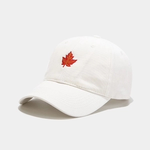 Close-up of red maple leaf embroidery on a white cotton baseball cap with twill texture