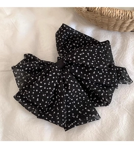 Detailed view of large French polka dot chiffon bow hair clip on elegant white fabric