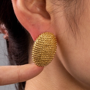 Golden oval stud earrings with fine beaded texture on model for a modern luxury look