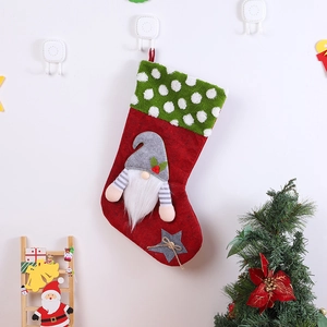 Détail d'une chaussette de Noël rouge en peluche avec gnome sans visage et revers à pois