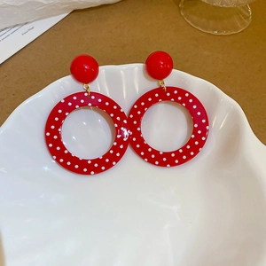 Close-up of vintage red polka dot resin hoop earrings on a decorative shell tray