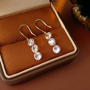 Detailed view of silver hook earrings with three zircon stones in a velvet jewelry box