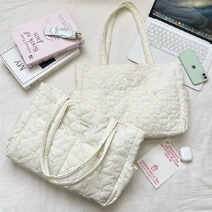 Flat lay of quilted floral tote bag with cherry embroidery next to laptop and phone