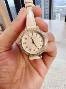 Close-up of champagne dial with crystal markers and white crocodile pattern leather strap