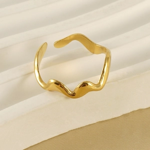 Détail d'une bague vague dorée ajustable sur un support d'exposition texturé blanc