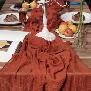 Terracotta cheesecloth table runner draped on a wooden table with vintage decor