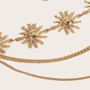 Detail van gelaagde gouden metalen tailleketting met zonvormige hangers
