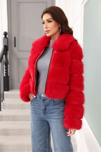 Detail of red faux fur jacket with zipper closure shown on model in a modern staircase