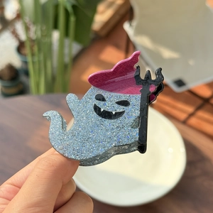 Close-up of a blue glitter ghost hair claw with a wizard hat and trident detail