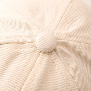 Detailed close-up of beige cotton twill baseball cap crown with premium fabric button