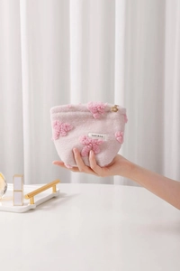 Close-up of pink plush cosmetic bag with floral texture and golden flower zipper