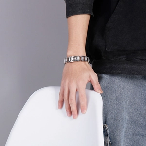 Man wearing heavy stainless steel skull bike chain bracelet against a grey background