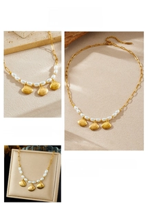 Détails des pendentifs en coquillage doré et perles ovales sur un collier à maillons