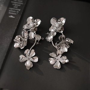 Détail de boucles d'oreilles fleur métallique avec perles en cascade et plaqué argent