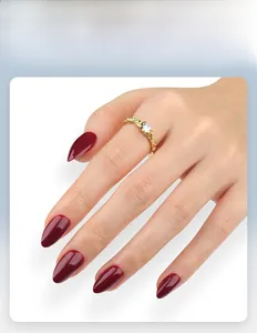 Close-up of wine red oval press-on nails with a minimalist gold ring on a hand
