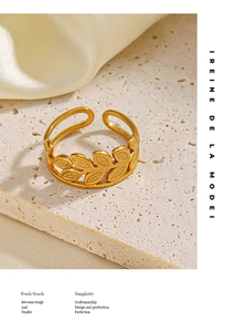Detail shot of a golden adjustable olive leaf ring on white marble and cream silk