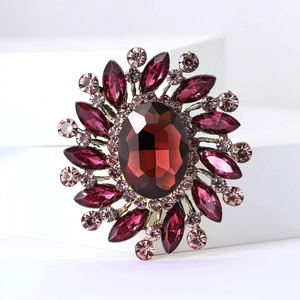Detailed close-up of a vintage sunburst brooch with deep red and pink rhinestones