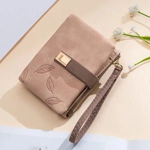 Detalle de la cartera rosa-beige de ante sintético con grabados de hojas y hebilla
