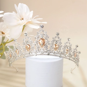 Detailed close-up of a silver tiara with champagne water-drop crystals and white rhinestones