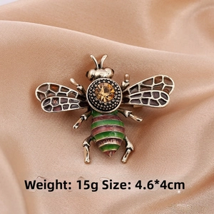 Macro view of vintage bee brooch with enamel wings and rhinestone detailing on silk