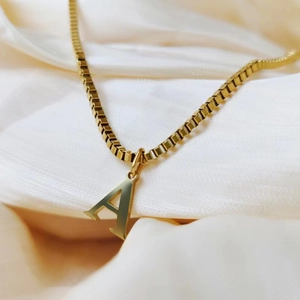 Macro shot of gold-plated capital letter A pendant on a classic box chain necklace
