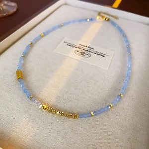 Détail de perles facettées bleu clair et d'espaceurs dorés sur un collier vintage chic