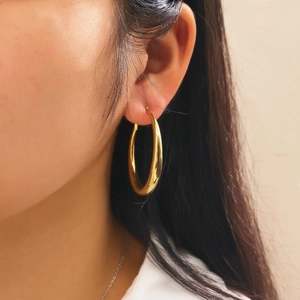 Side view close-up of large minimalist gold hollow hoop earrings with polished metal finish