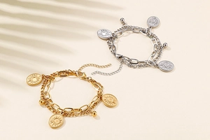 Detail of celestial coin charms on layered gold and silver stainless steel bracelets