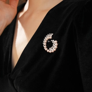 Macro detail of French vintage spiral brooch with pink pearls and zircon on black velvet