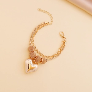 Macro detail of a double-layered gold heart pendant necklace with intricate woven beads