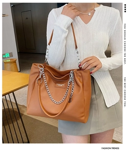 Detailed macro view of brown litchi grain leather tote with a silver metal chain accent