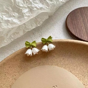 Macro detail of lily of the valley earrings with green bow and translucent petals