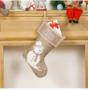 Linen Christmas stocking with snowman print and gift box hanging on a festive mantel