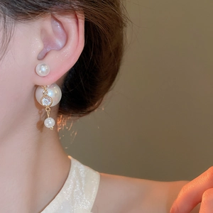 Detail view of elegant double-sided pearl earrings with gold accents and cubic zirconia